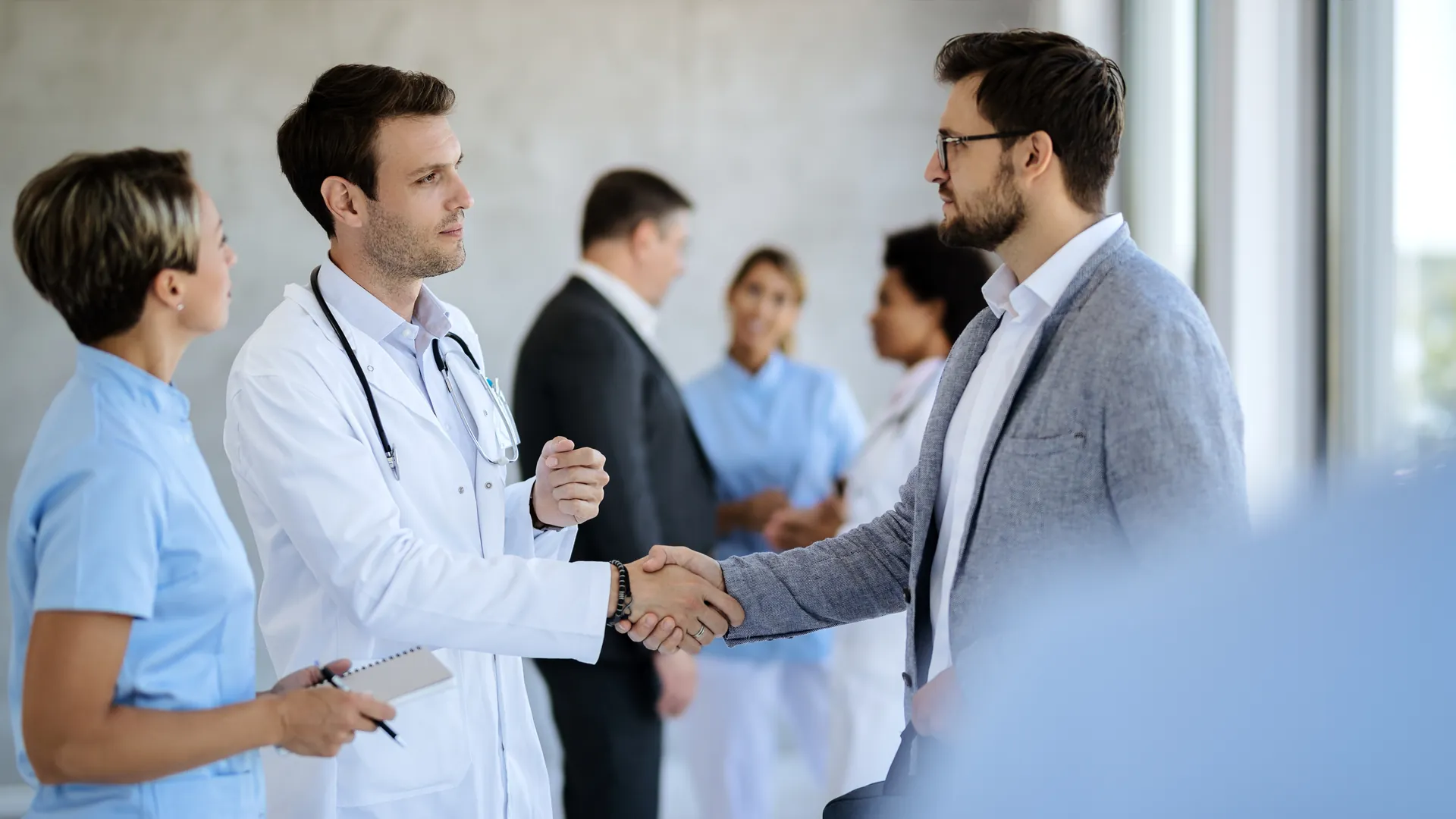 Profesionales de salud y un directivo estrechándose la mano en un hospital.